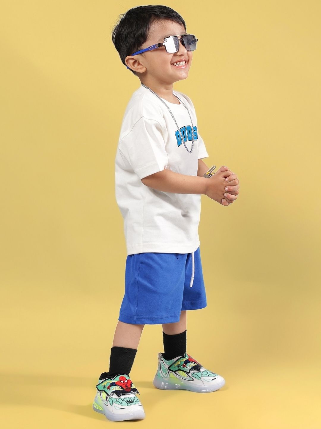 Child wearing SUPER AWESOME CO-ORD FOR BOYS AND GIRLS OFF WHITE ROYAL BLUE with stylish sunglasses and sneakers on yellow background