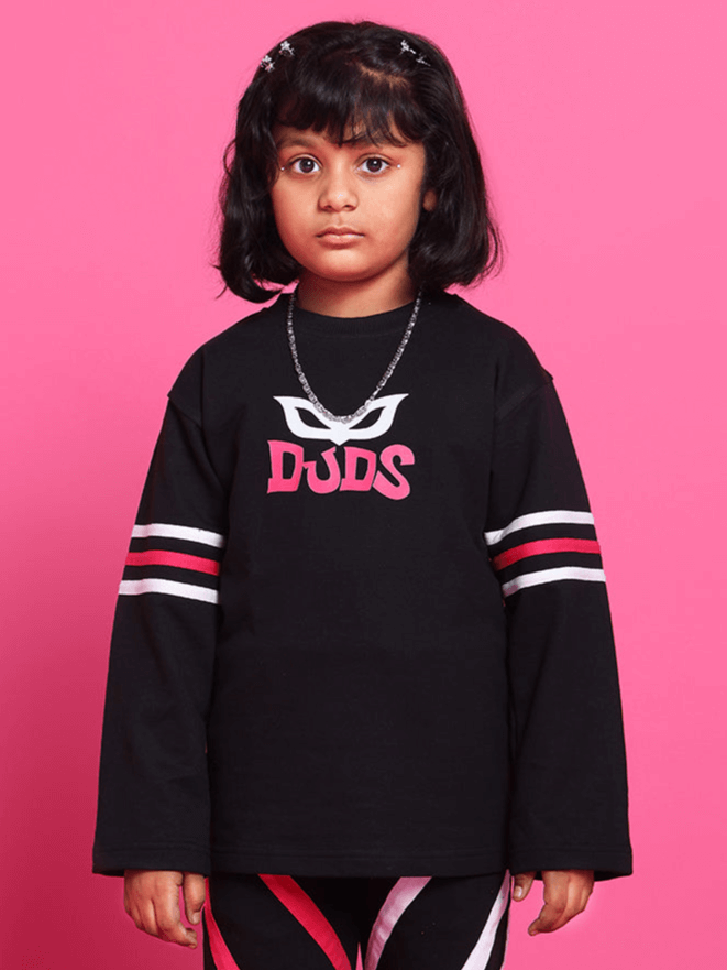 Child wearing SUPER CHAMP OVER-SIZED SWEATSHIRT FOR BOYS GIRLS BLACK against a pink background.