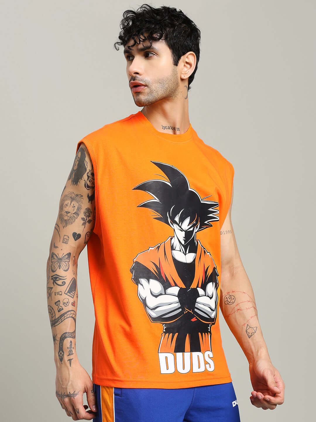 Man wearing orange Super Saiyan gym t-shirt with custom fit option by DUDS, featuring bold anime design and sleeveless style.