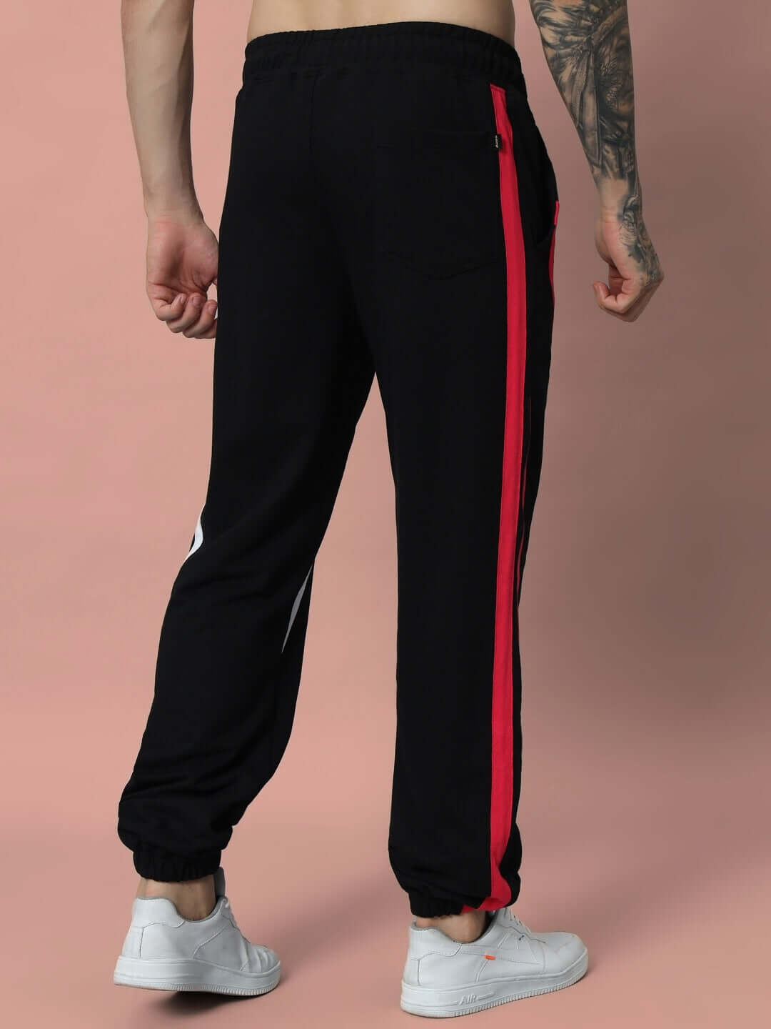 Man wearing SWATHE Colorful Stripe Joggers in Black, featuring vibrant red side stripes and stylish fit for casual comfort.