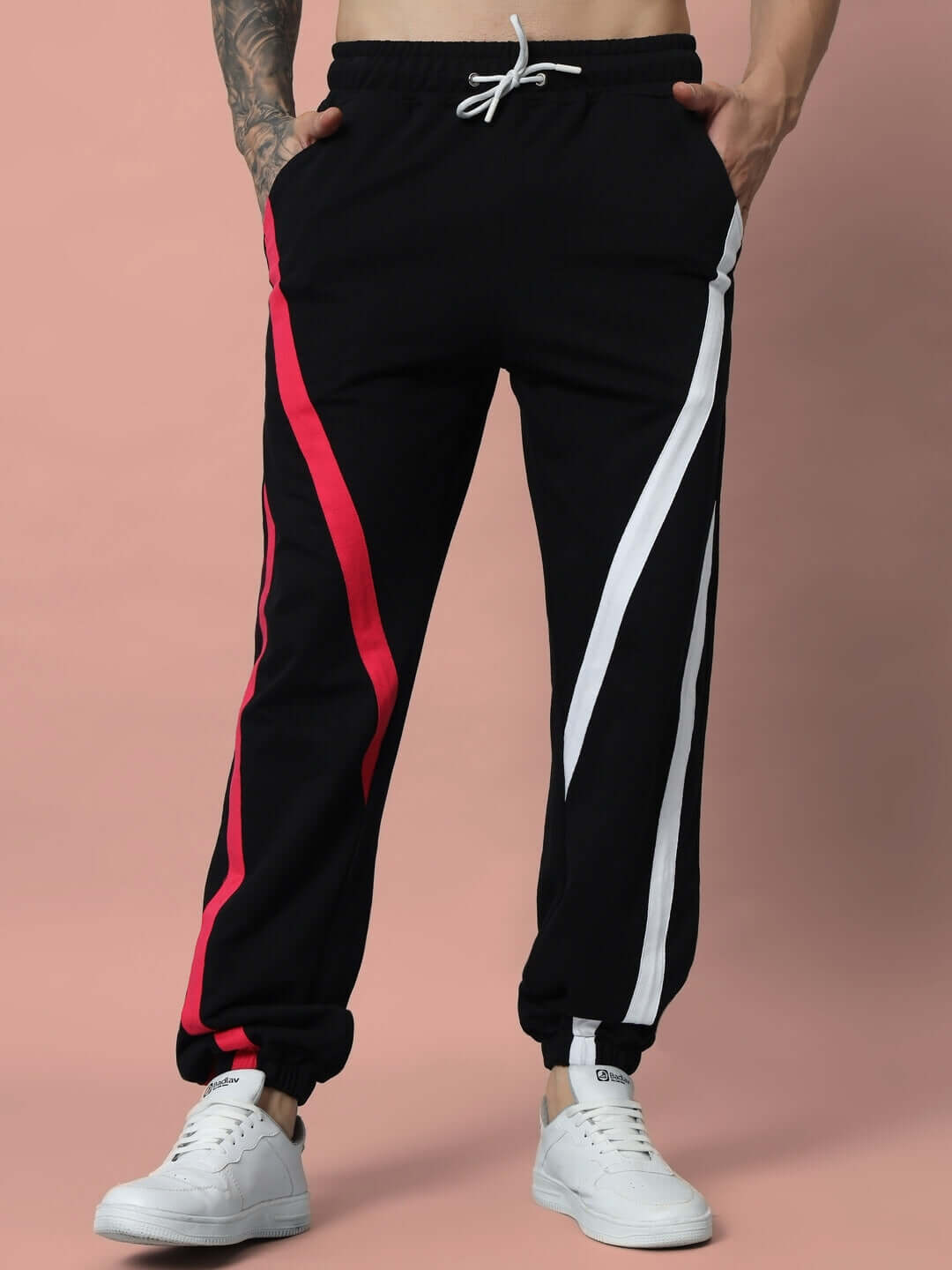 Alt Tag: SWATHE black joggers with colorful stripes, made to order and customizable, worn with white sneakers against a beige background.