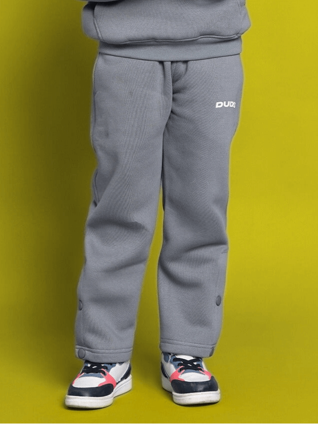 Child wearing grey Tabby fleece pants suitable for boys and girls, standing against a yellow background.