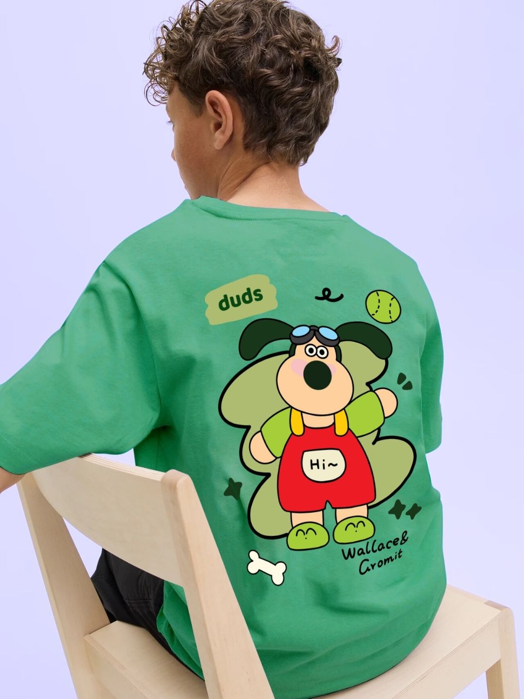 Child wearing TADDY PUPPY T-SHIRT FOR BOYS AND GIRLS GREEN with cartoon design sitting on chair back view