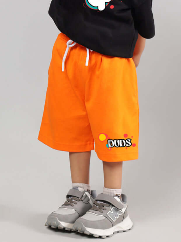 Child wearing orange 'Take the Step' shorts by DUDS, paired with grey sneakers; ideal for boys and girls, customizable fit available.