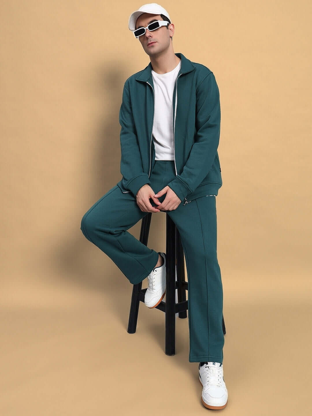 Model wearing teal green shaggy zipper fleece co-ord set from DUDS, seated on a stool against a beige backdrop.