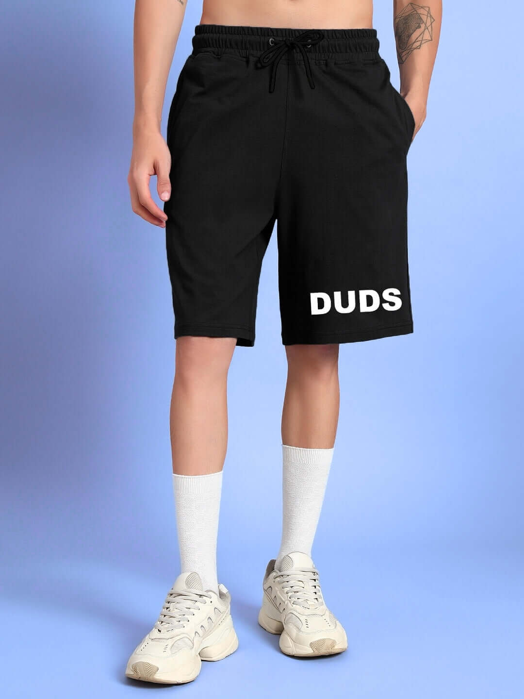 Model wearing black 'THINK BIG SUMMER SHORTS' by DUDS, featuring a customizable fit option for tailored comfort. Casual and stylish design.