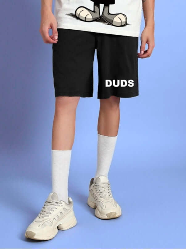Model wearing THINK BIG SUMMER COTTON SHORTS BLACK with sneakers and socks, showcasing comfort and style.