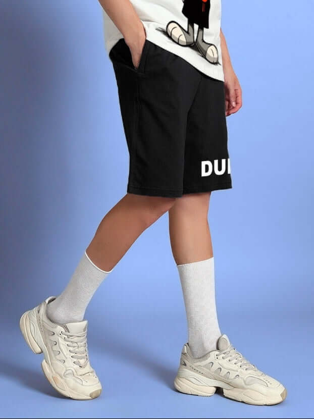 Person wearing THINK BIG SUMMER COTTON SHORTS BLACK with white socks and sneakers, demonstrating comfort and style for casual outfits.