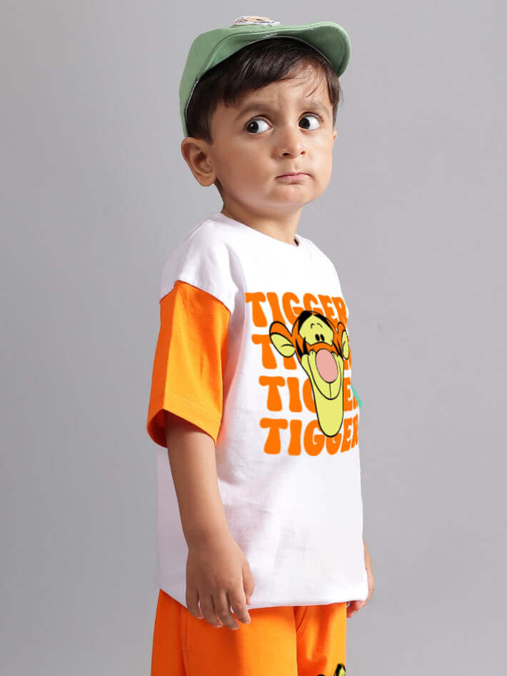 Child wearing a white oversized tiger graphic T-shirt with orange sleeves and matching shorts.