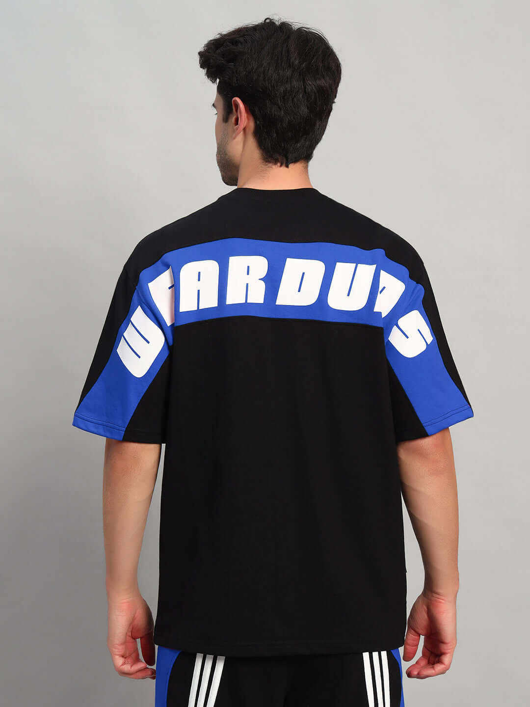 Man wearing TITAN OVER-SIZED T-SHIRT BLACK-BLUE with bold white letters on back.