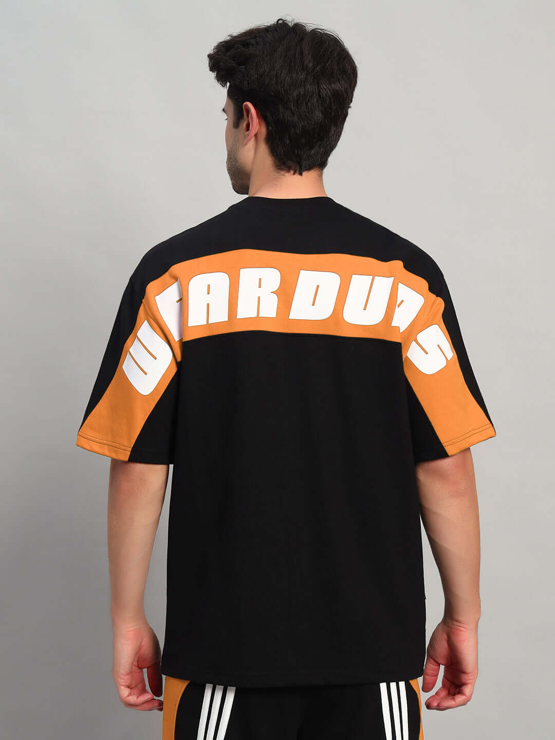 Back view of TITAN OVER-SIZED T-SHIRT BLACK-ORANGE made with premium cotton fabric, showcasing stylish design and bold lettering.