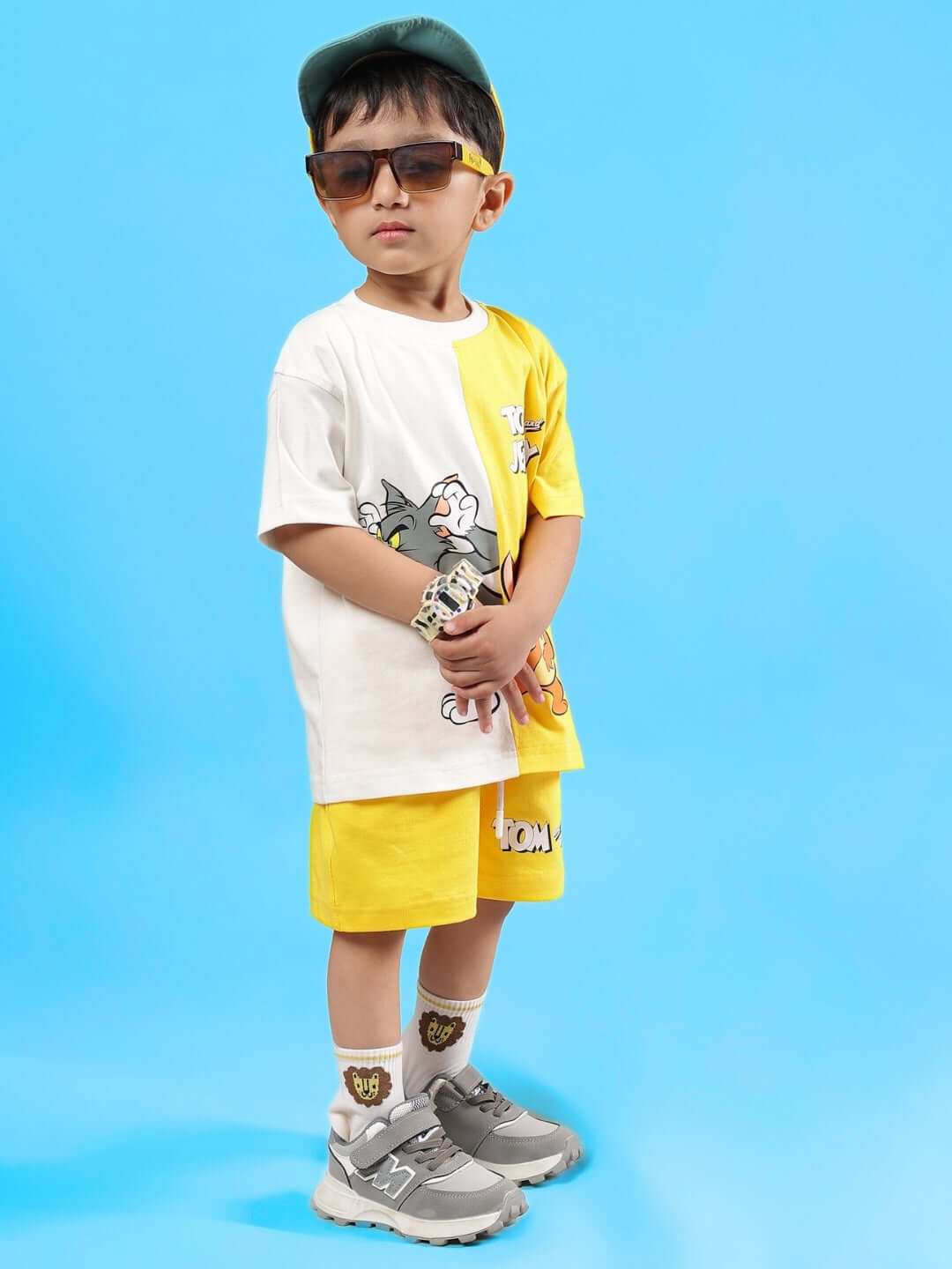 Child wearing Tom & Jerry yellow co-ord set with sunglasses and cap.