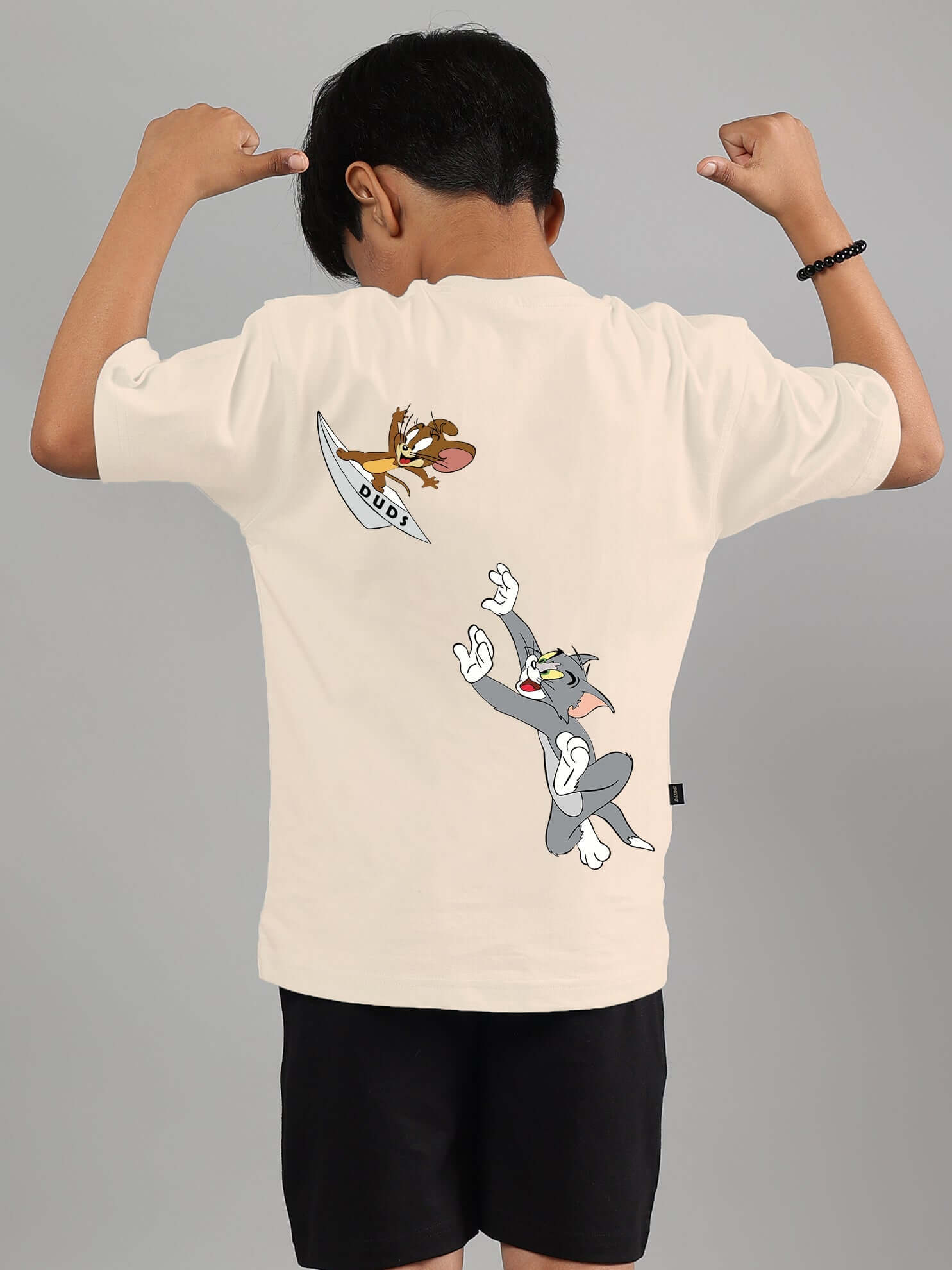 Boy wearing off-white Tom & Jerry t-shirt, featuring cartoon characters, product by DUDS, customizable fit available.
