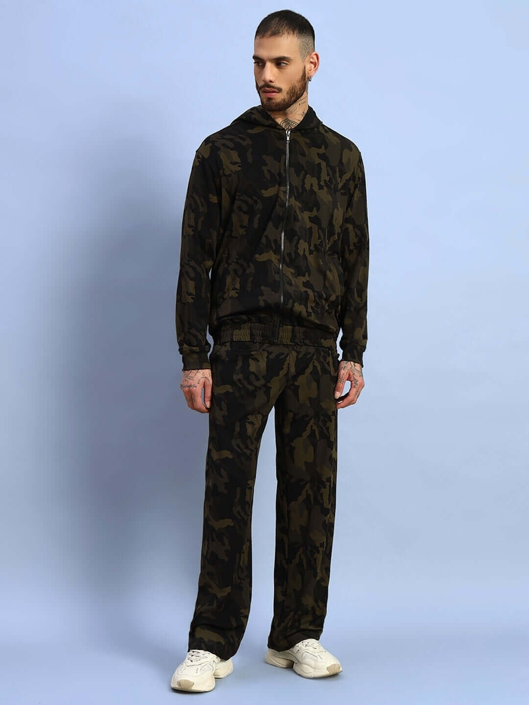 Model wearing camo green trench camouflage jacket with matching pants and white sneakers.