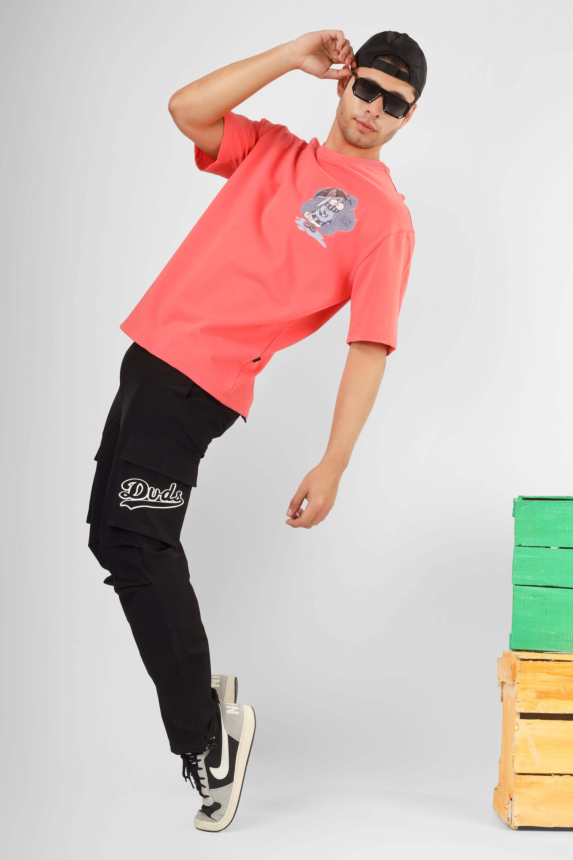 Model wearing dark grey Myriad Relaxed Fit Cargo Pants with custom fit option, paired with a vibrant graphic tee and sneakers.