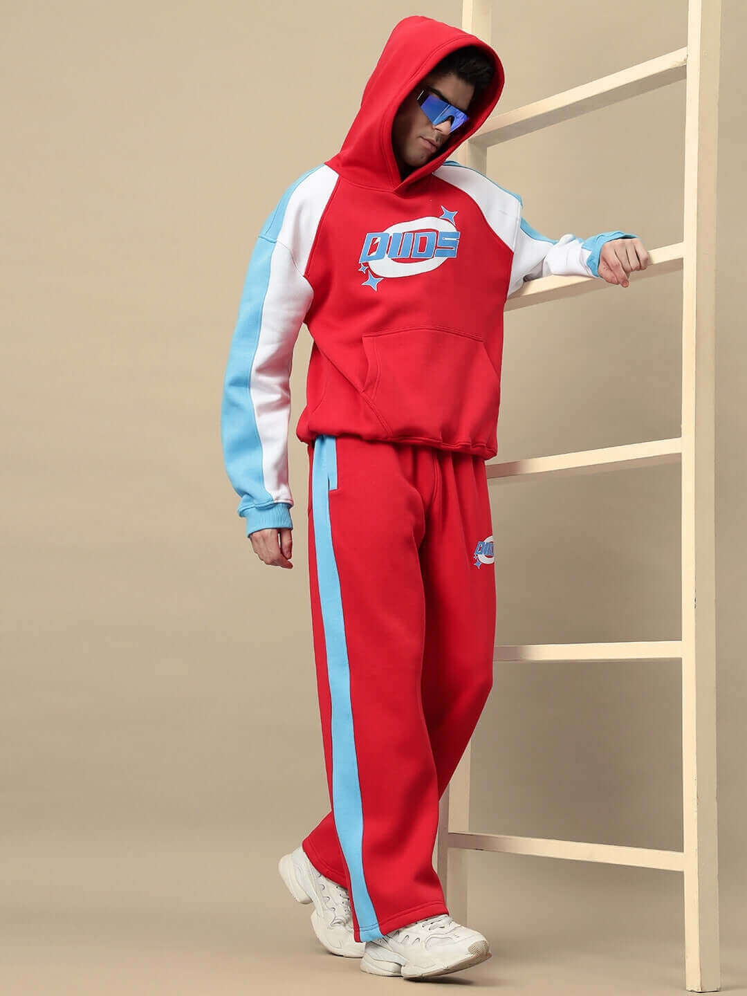 Model wearing TRUNKIT COLORBLOCK CO-ORD in red with blue and white accents, showcasing a bold streetwear look with hooded top and joggers.