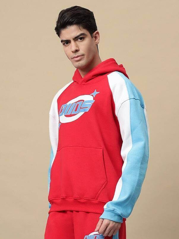 Man wearing TRUNKIT COLORBLOCK CO-ORD in red with blue and white sleeves, featuring a graphic design on the front.