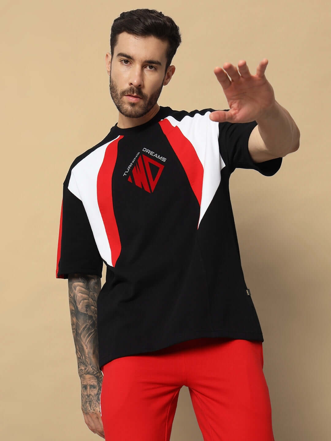 Model wearing black TURNING DREAMS REFLECTOR oversized t-shirt with red and white accents, paired with red pants.