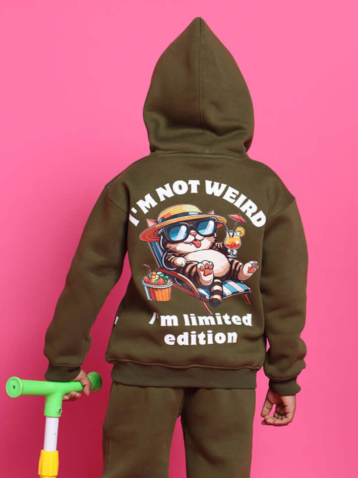 Child wearing an olive green oversized fleece hoodie with "I'm Not Weird, I'm Limited Edition" print on the back, holding a scooter.