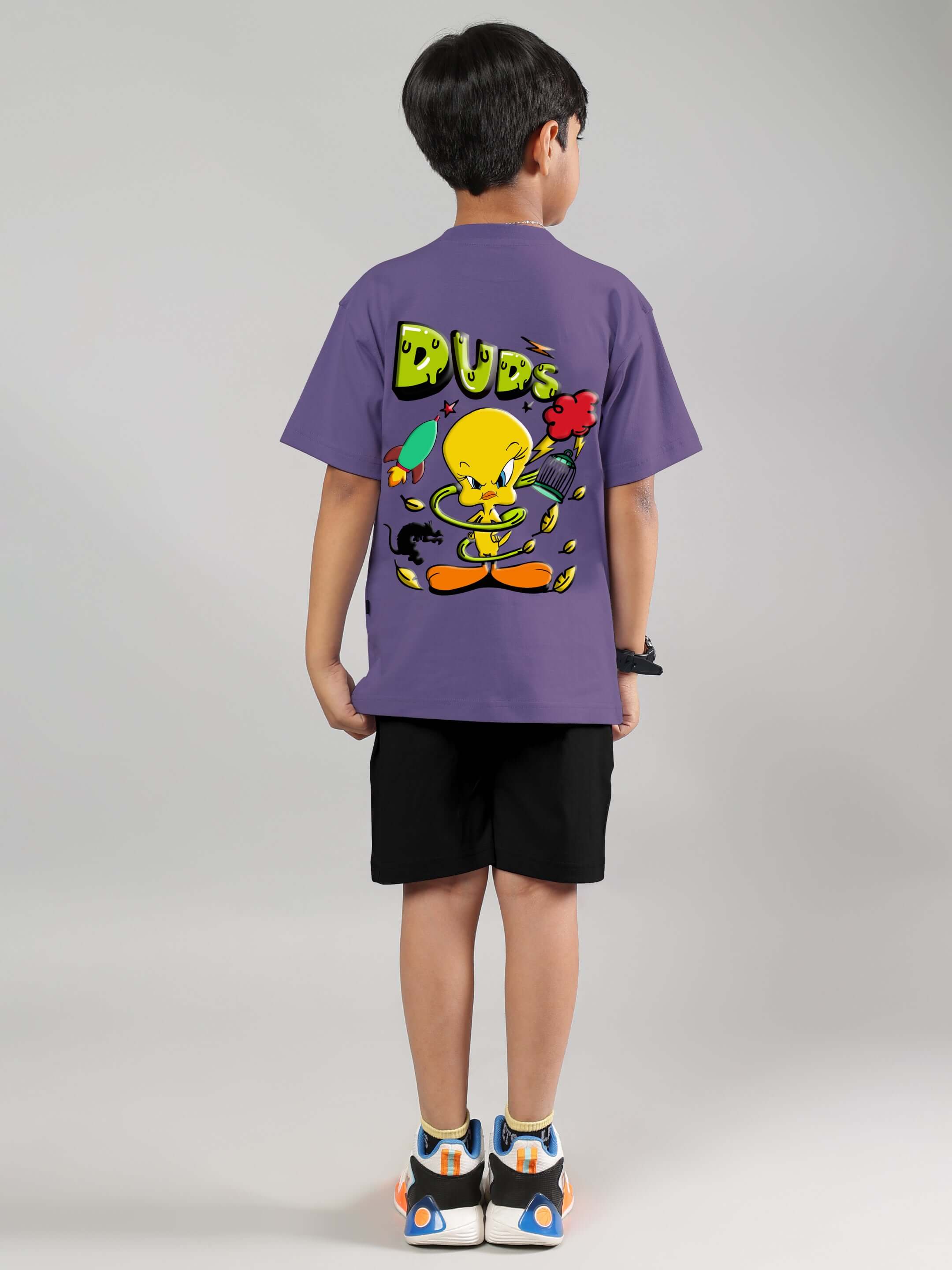 Boy wearing wisteria purple Tweety co-ord outfit with black shorts from DUDS, featuring vibrant back design for kids.