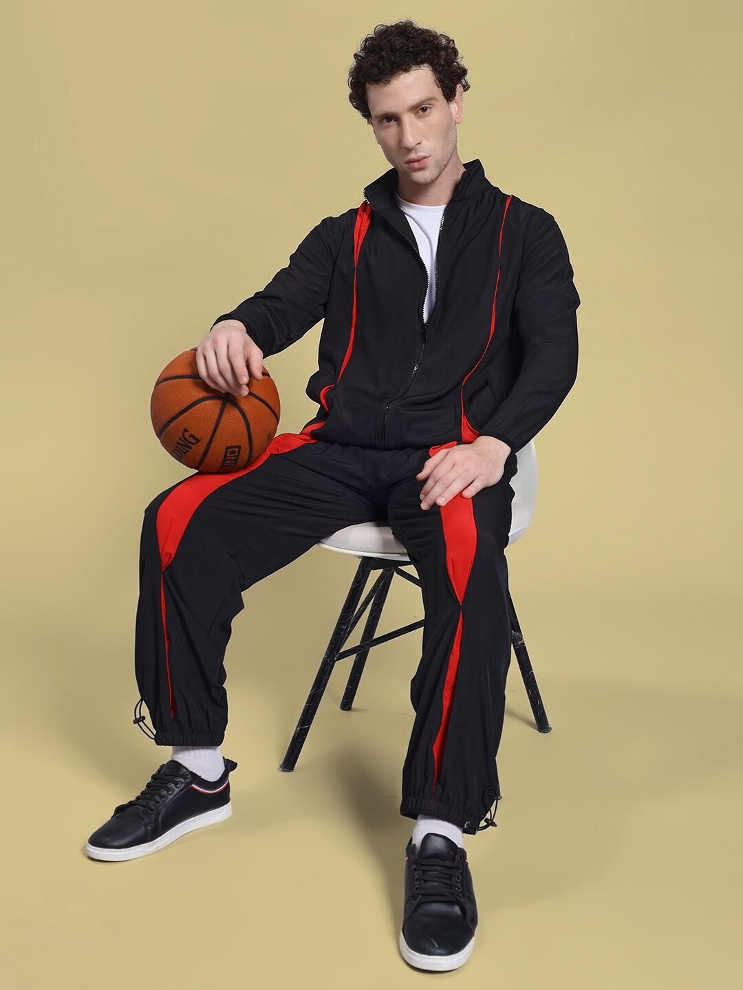 Man wearing UNISON RELAXED FIT JACKET BLACK RED, holding basketball, showcasing stylish casual fashion.