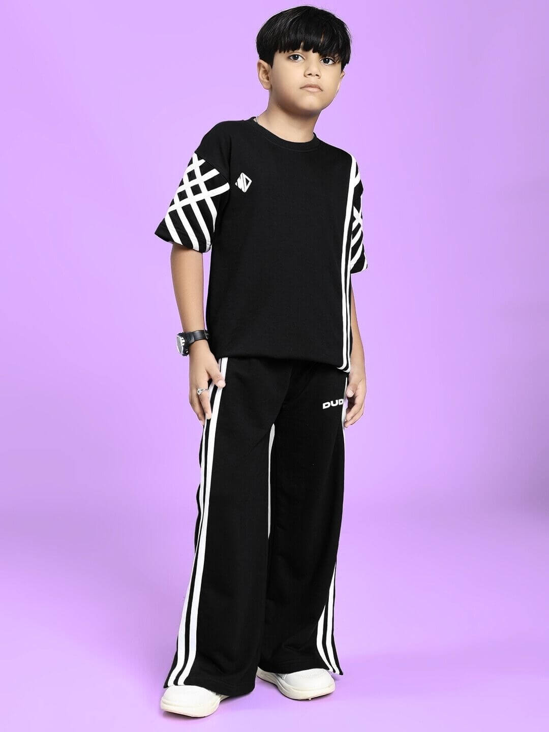 Child wearing UNITED STRIPE CO-ORD SET FOR BOYS GIRLS BLACK, featuring bold stripe detailing and a sleek black base, on a purple background.