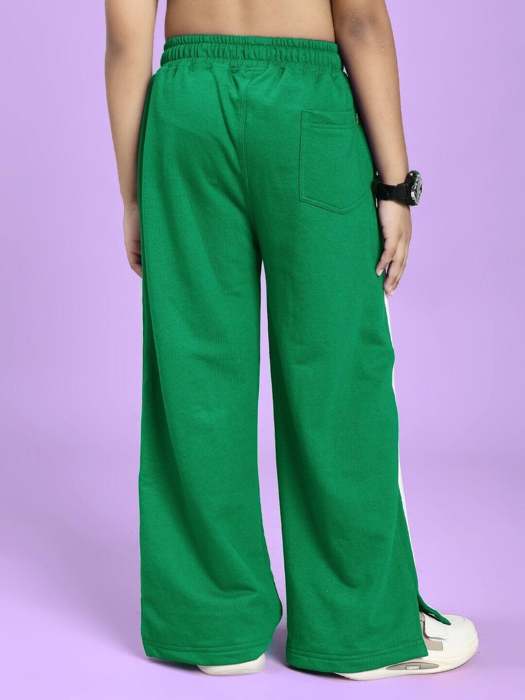 Child wearing UNITED STRIPE JOGGER FOR BOYS AND GIRLS GREEN with sporty stripes on purple background