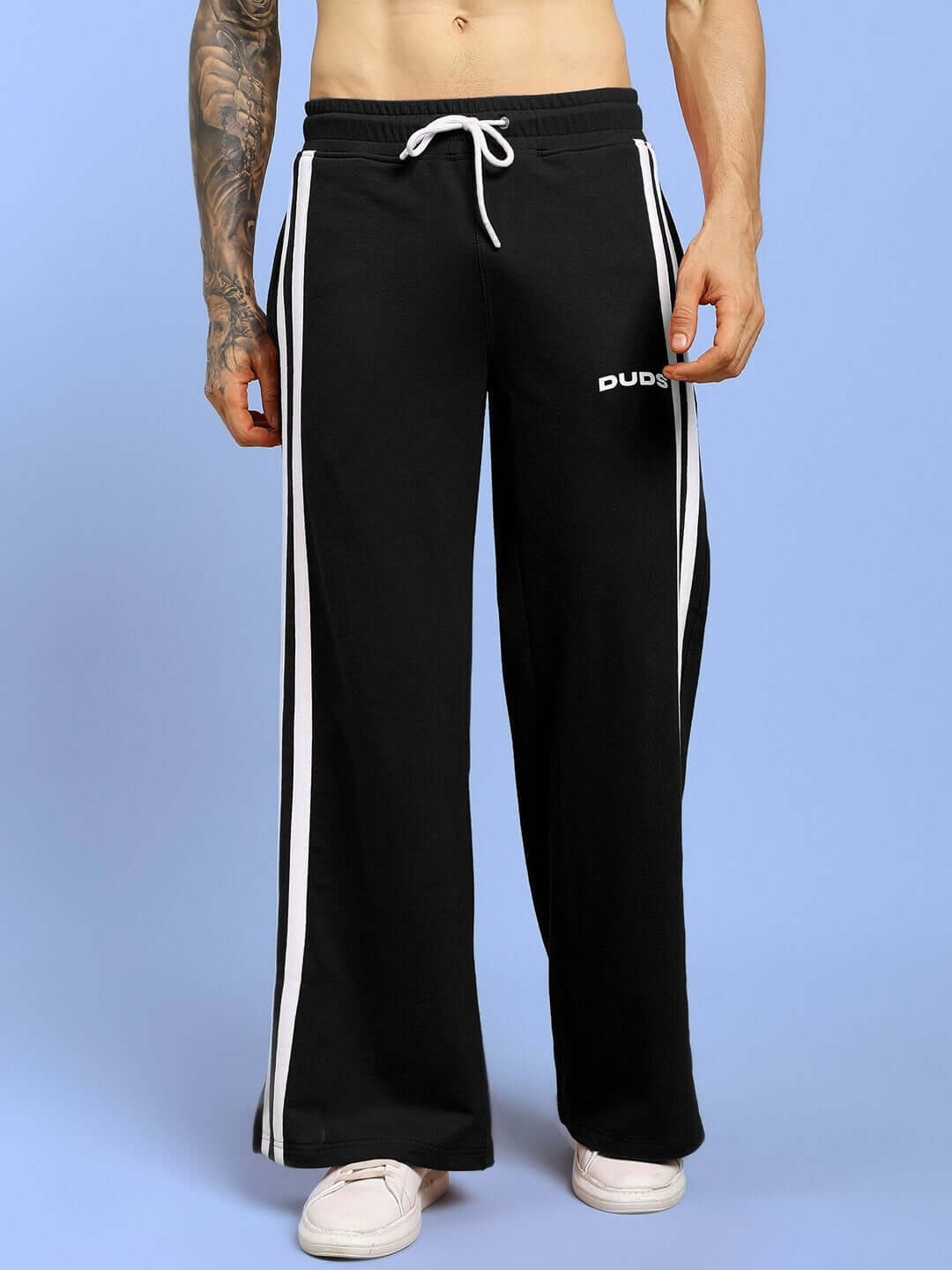 Model wearing black United Stripe Joggers by DUDS, showing side stripes and drawstring waist, perfect for casual wear and custom fit options.
