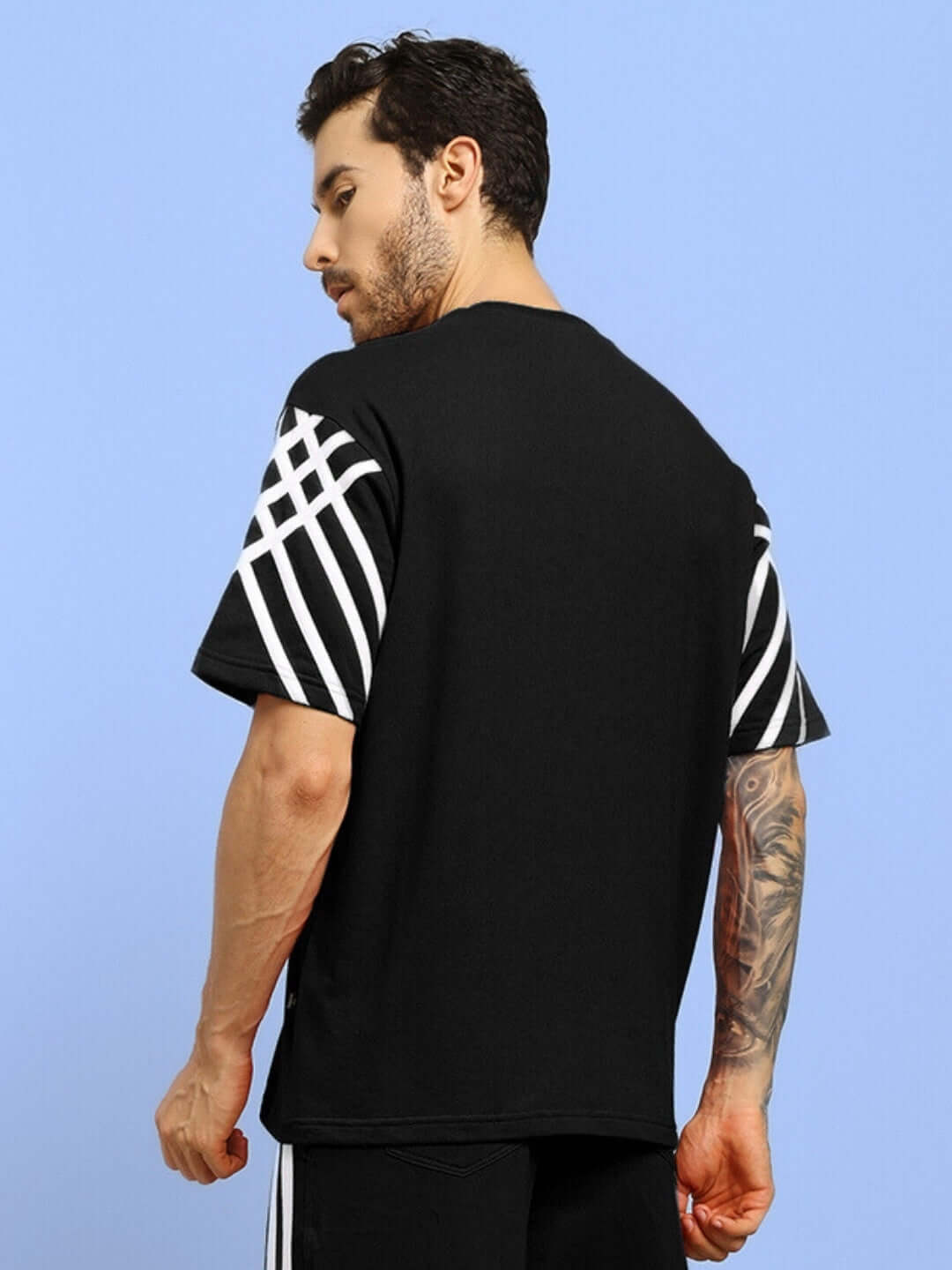 Black oversized t-shirt with white stripes, made of premium cotton French terry, worn by model. Ideal for casual style.