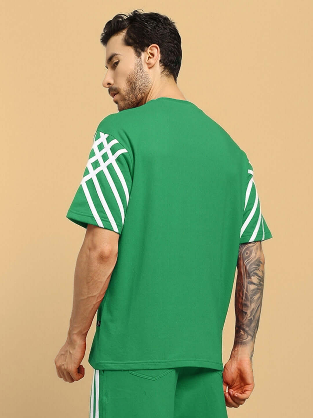 Model wearing United Stripe oversized green t-shirt with white stripes, made from premium cotton French terry fabric, side view.