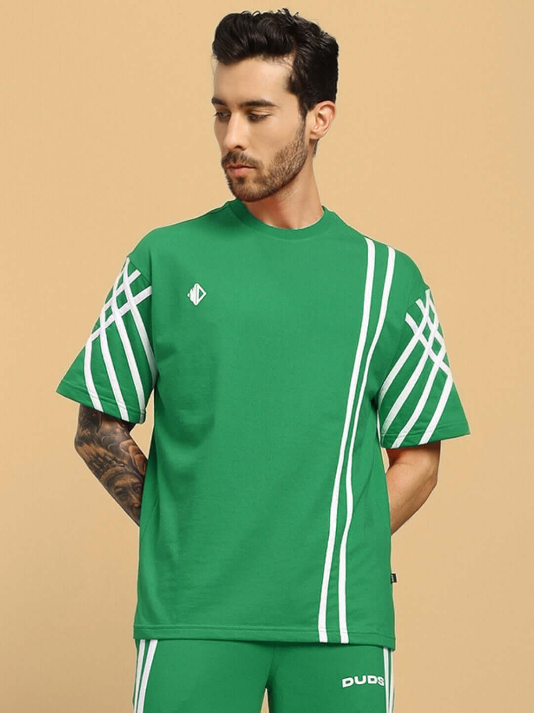 MAN WEARING UNITED STRIPE OVER-SIZED GREEN T-SHIRT IN PREMIUM COTTON FRENCH TERRY, SHOWCASING BOLD WHITE STRIPES ON SLEEVES AND FRONT.