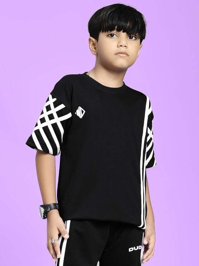 Child wearing UNITED STRIPE T-SHIRT FOR BOYS AND GIRLS BLACK with bold stripe design on sleeves, standing against a purple background.