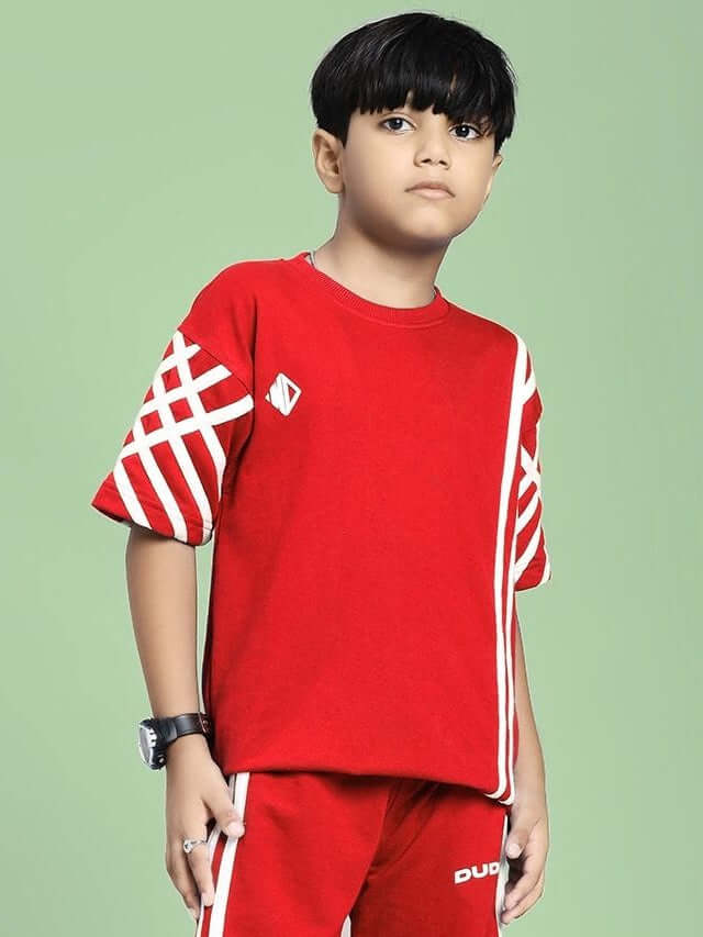 Boy wearing UNITED STRIPE T-SHIRT FOR BOYS AND GIRLS RED with sporty stripe design on green background