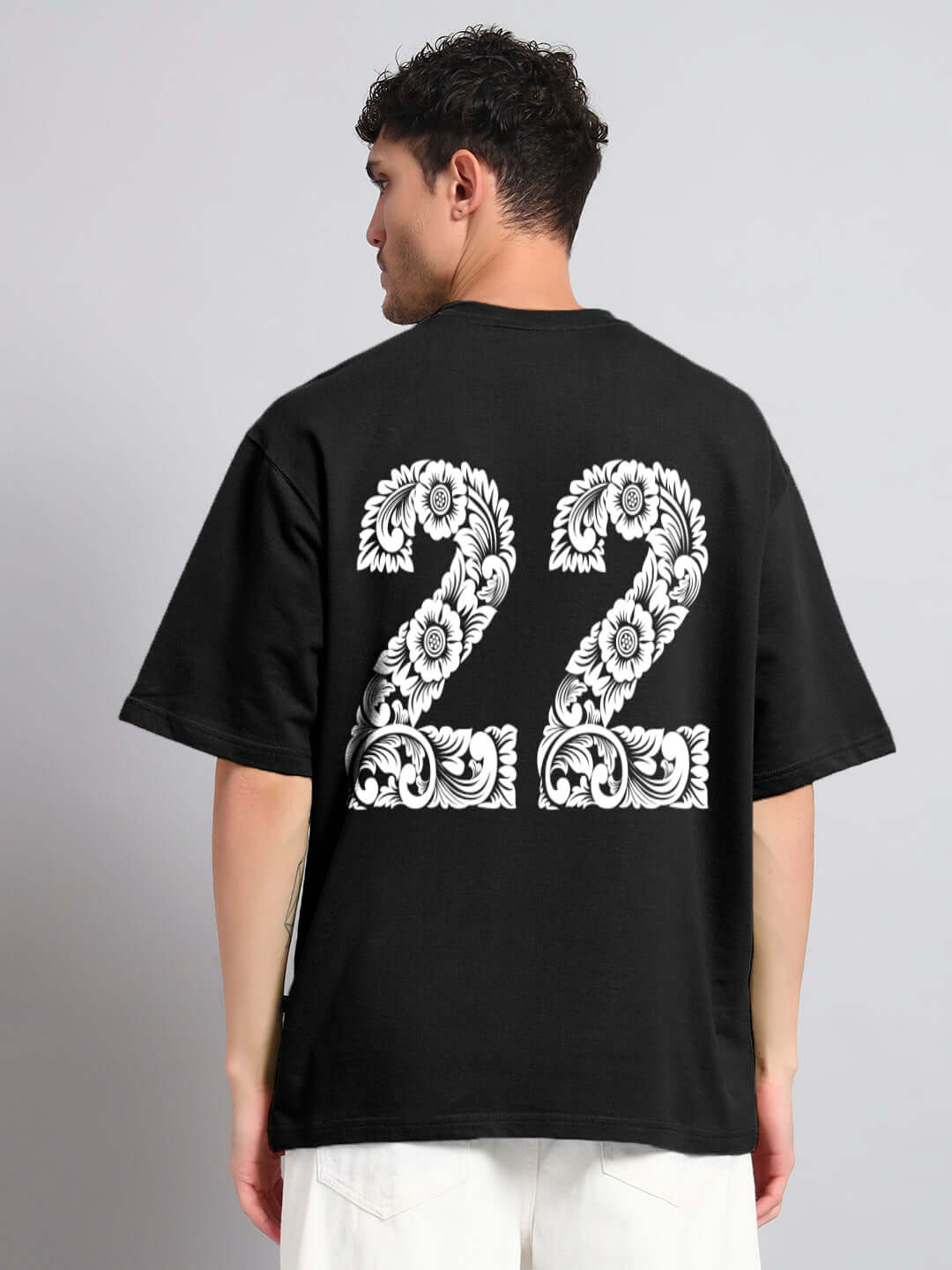 Back view of Urban Petal Black Oversized T-shirt with floral '22' design, made of premium cotton and elastane blend.