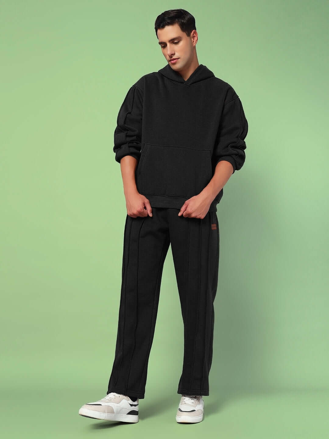 Model wearing Urban Solid Plated Fleece Co-Ord Black set with hoodie and joggers against a green background.