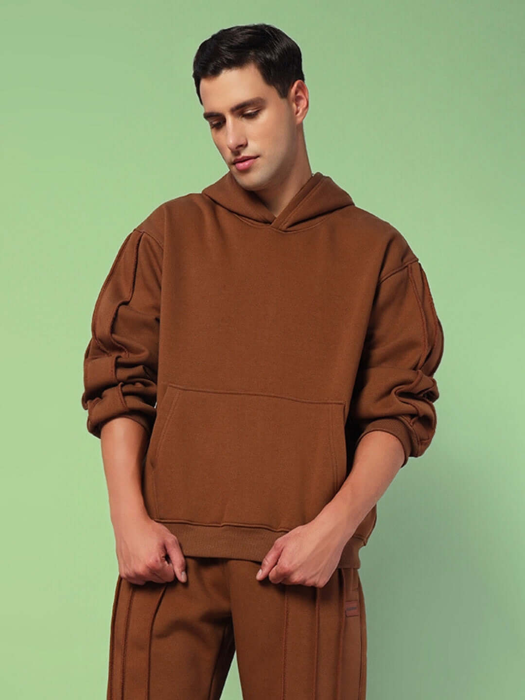 Man wearing Urban Solid Plated Fleece Hoodie Brown in a studio setting, showcasing the minimalist design and comfortable fit.