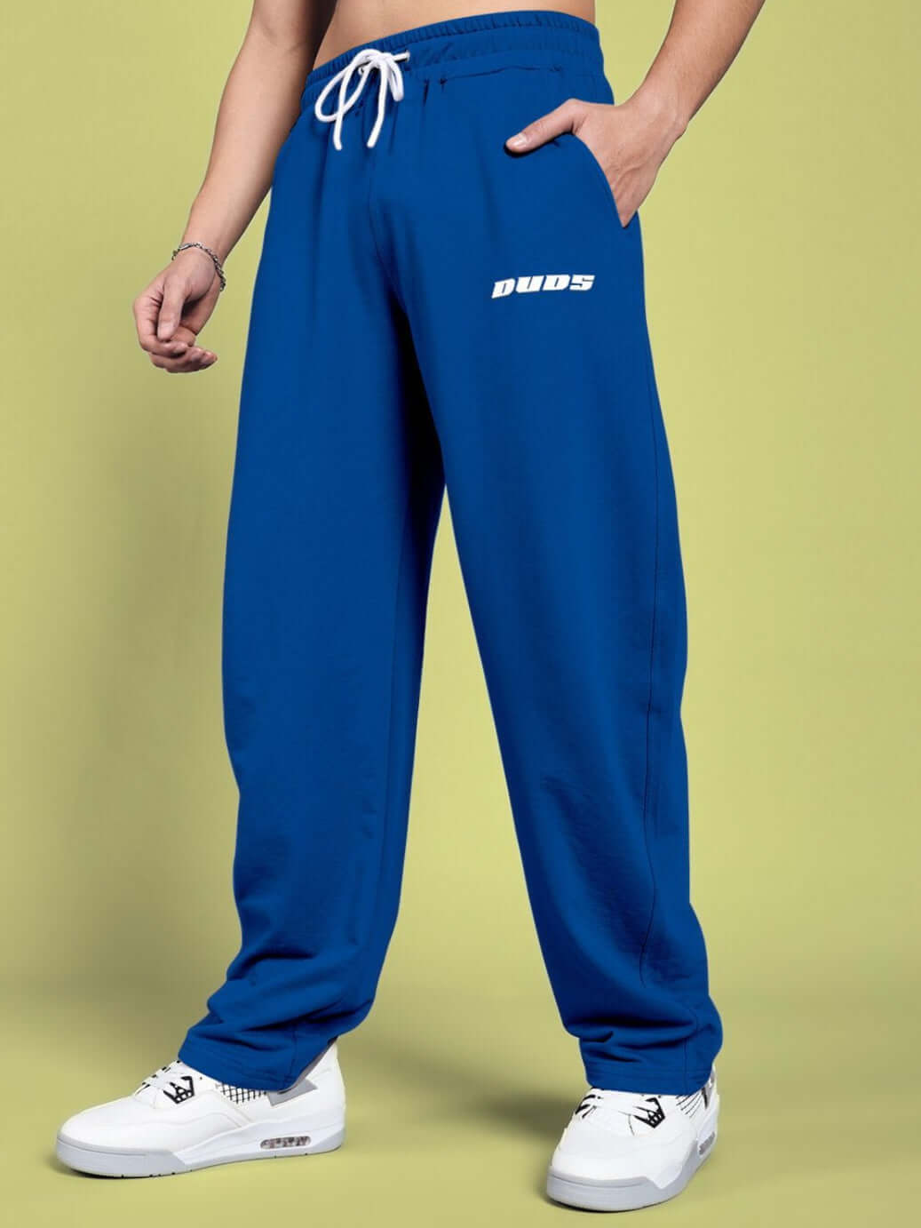 Blue vanilla relaxed-fit joggers by DUDS, modeled with white sneakers against a light green background.