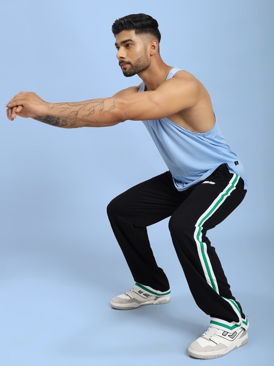 Man wearing VELO GREEN STRIPE RELAXED FIT JOGGER BLACK squatting in athletic pose