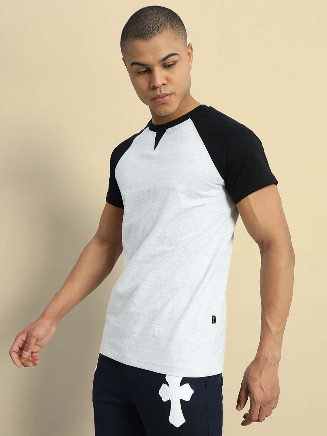 Man wearing a VERPA regular fit grey melange t-shirt with black sleeves, made of 100% cotton heavy gauge fabric, against a beige background.
