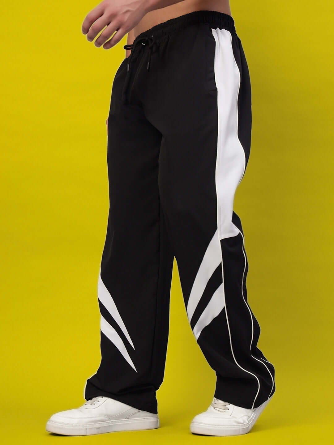 Person wearing black versatile parachute cargo pants with white stripes against a yellow background.