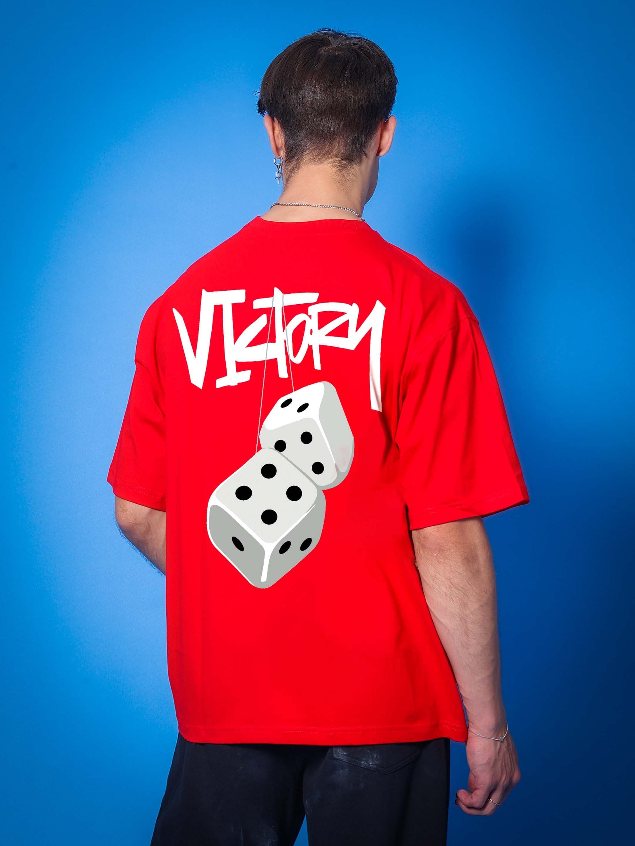 Man wearing a red VICTORY over-sized t-shirt with dice graphic, customizable fit available, displayed on a blue background.