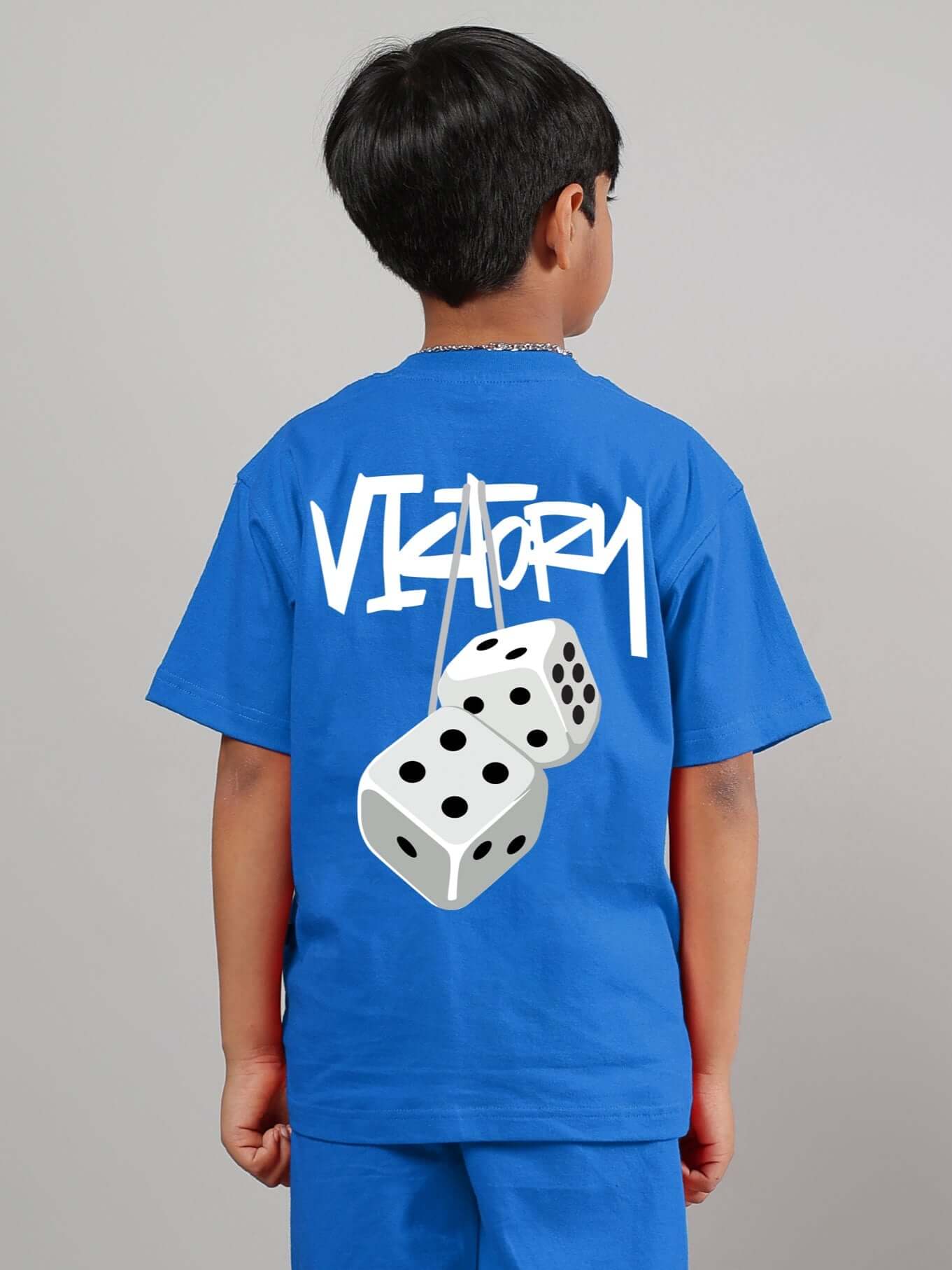 Child wearing blue Victory T-shirt with dice graphic, suitable for boys and girls, designed by DUDS.