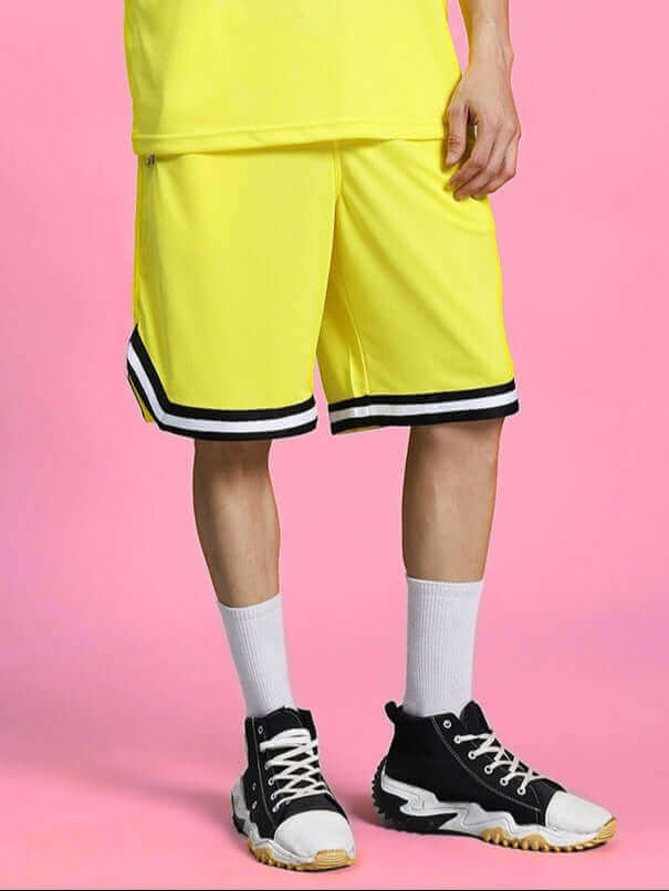 VIGOR REGULAR FIT SHORTS YELLOW displayed with black stripe detail, worn with black sneakers and white socks on pink background.