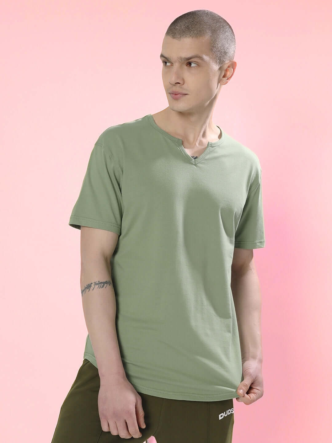 Model wearing sage green Viking regular fit t-shirt made of premium 100% cotton fabric, photographed against a pink background.
