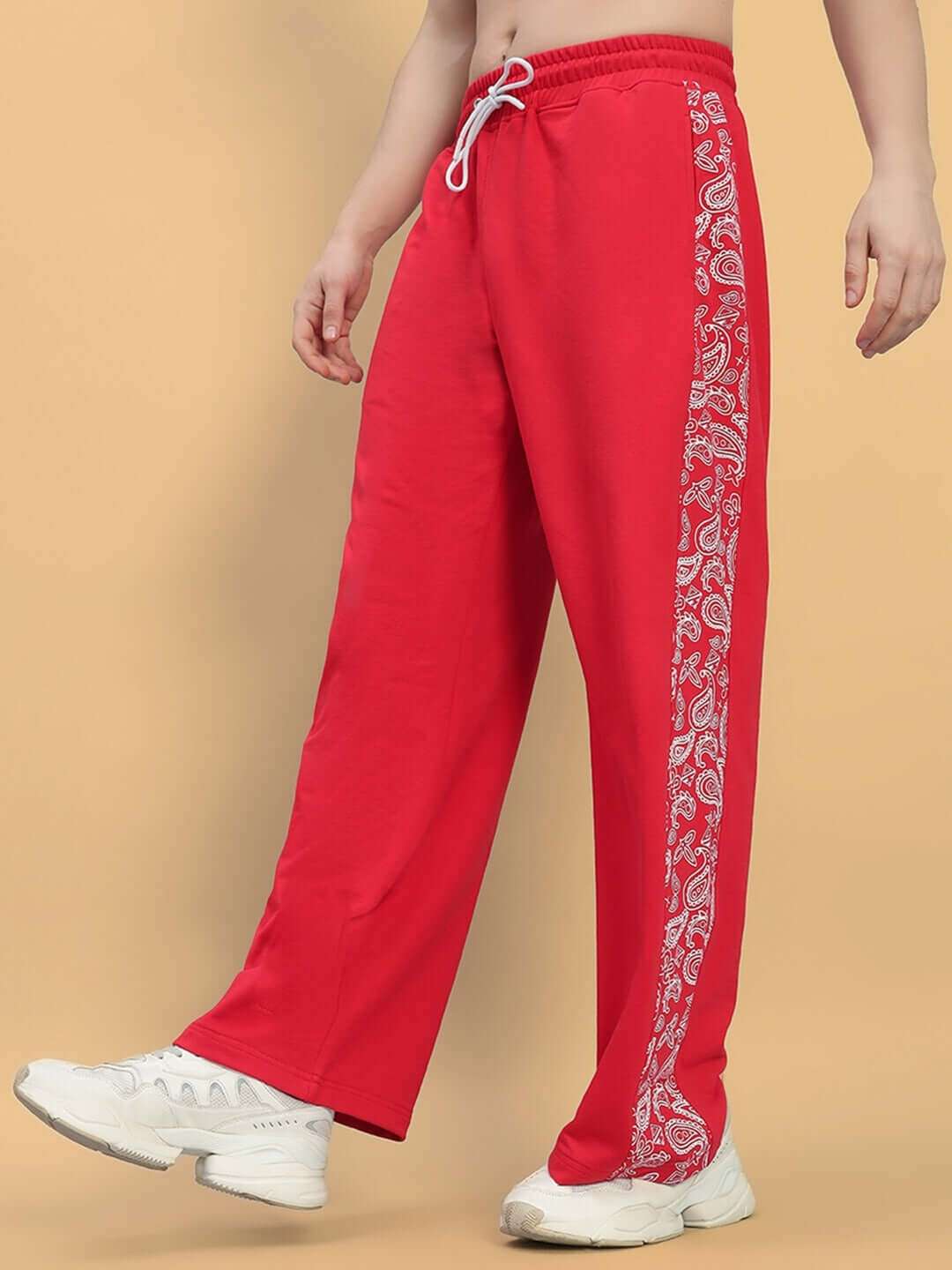 Person wearing Waltz Relaxed Fit Joggers in red with paisley pattern along sides and white sneakers, showcasing casual comfort.