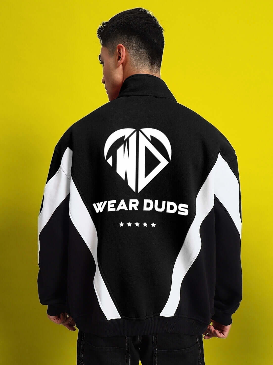 Back view of WD ALFA Fleece Colorblock Jacket in black, featuring bold white graphics and 'Wear Duds' text on a vibrant yellow backdrop.
