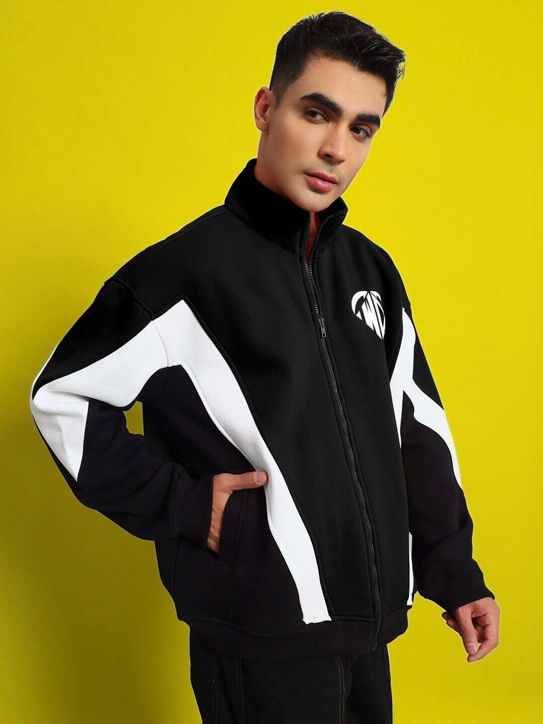 WD ALFA Fleece Colorblock Jacket in black and white, featuring a bold design and custom fit options. Model wearing jacket against yellow background.