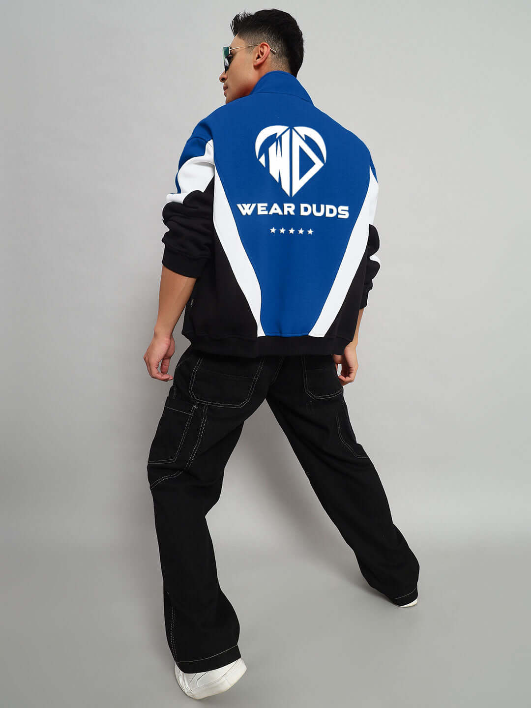 Person wearing WD ALFA Fleece Colorblock Jacket in blue with Wear Duds logo, showcasing back design and flare jeans.