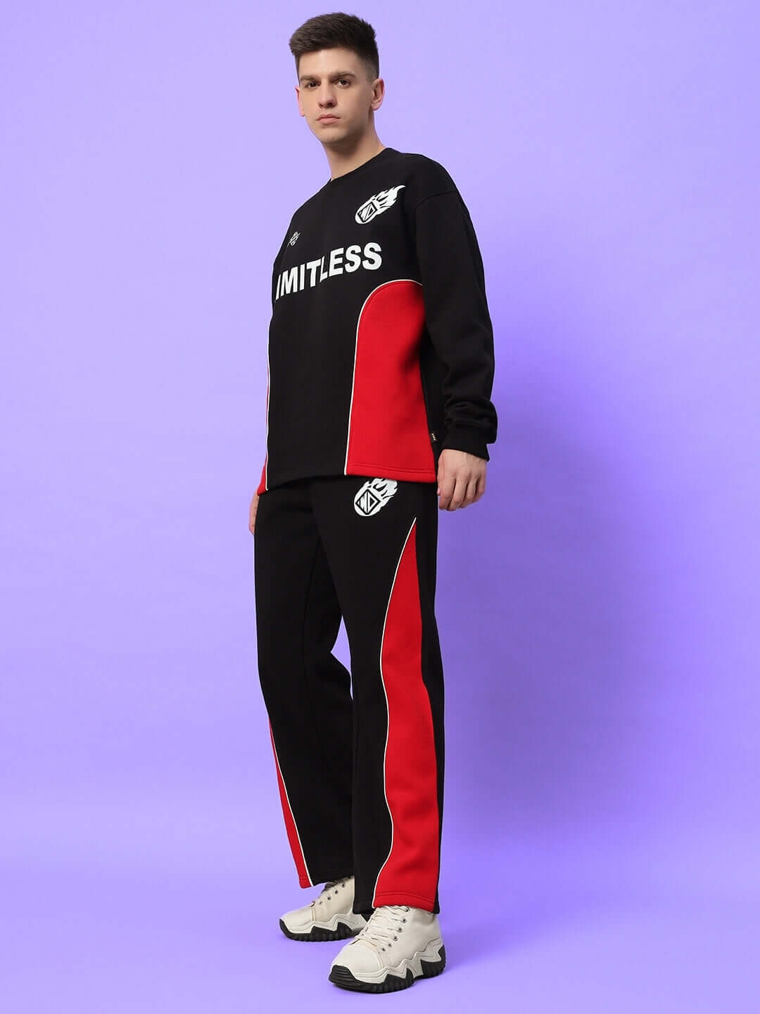 Model wearing WD FIREBALL COLORBLOCK CO-ORD BLACK RED with striking black-red design, hoodie and joggers, against a purple background.