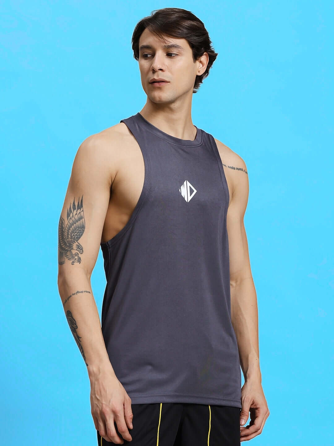 WD STRINGER SLEEVELESS GYM T-SHIRT GREY on model against blue background, showcasing design and fit.